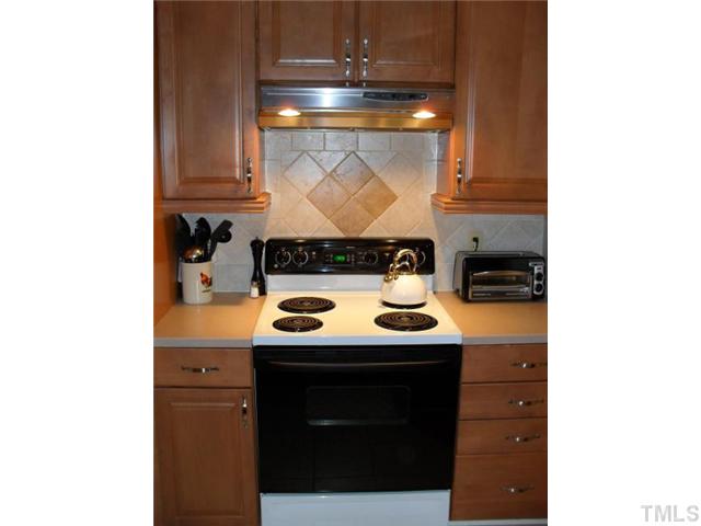 4400 Pickwick Drive Raleigh, NC 27613 - Photo 3 of 12 Kitchen details include tons of cabinet space including pull out drawers with soft close and lazy-susan storage. Additional features include cabinetry crown molding and light rail as well as decorative tile backsplash behind stove.