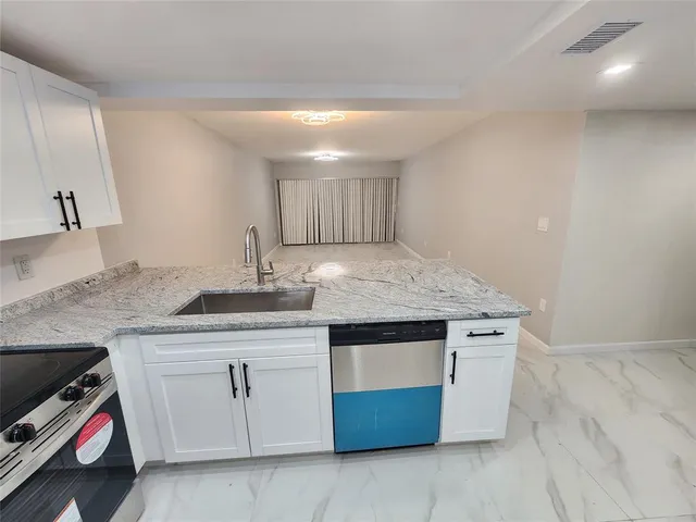 a kitchen with granite countertop a sink and a stove with wooden floor