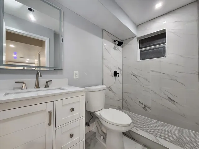 a bathroom with a granite countertop toilet sink and mirror