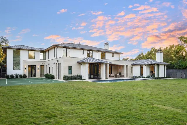 a large white house with a big yard and potted plants in front of it
