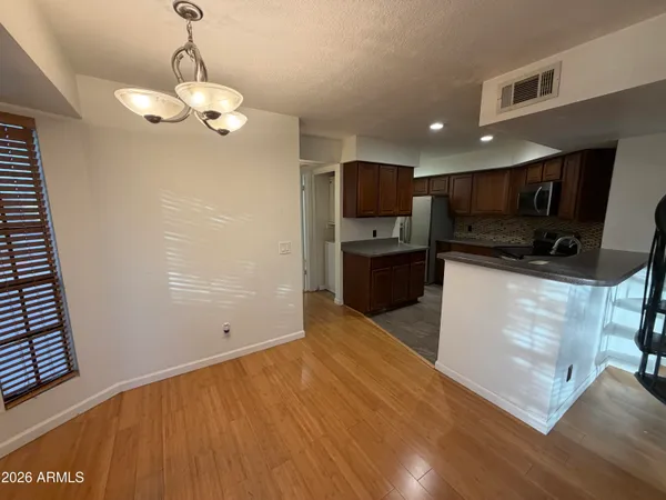 a view of kitchen with stainless steel appliances granite countertop a sink a stove top oven a refrigerator with wooden floors