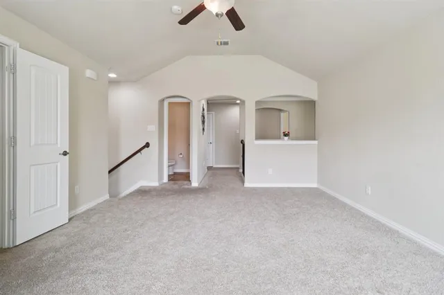 en empty room with ceiling fan and kitchen view