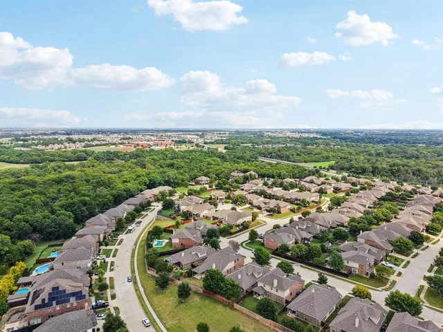 an aerial view of a residential houses with outdoor space and trees