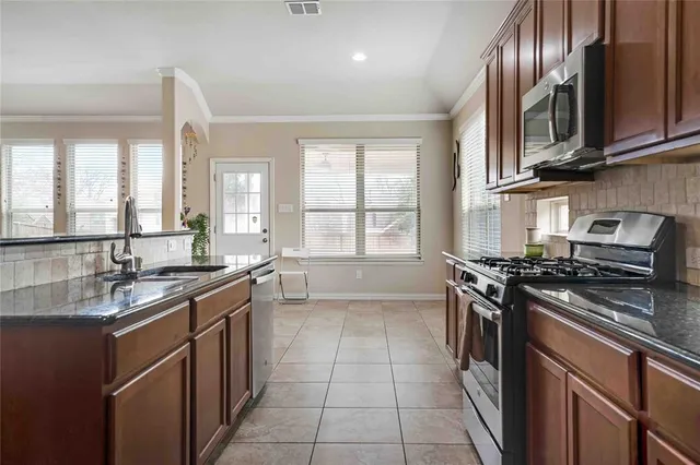 a large kitchen with stainless steel appliances granite countertop a stove and a sink