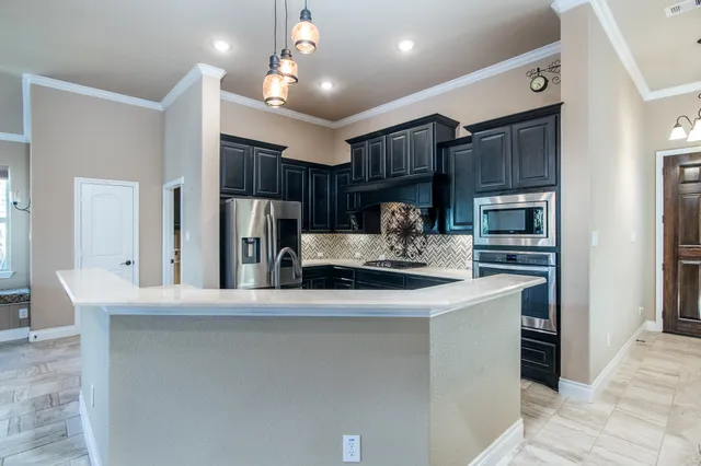 a kitchen with kitchen island stainless steel appliances a sink cabinets and a counter top space