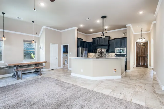 a view of kitchen with kitchen island stainless steel appliances a sink cabinets and living room view