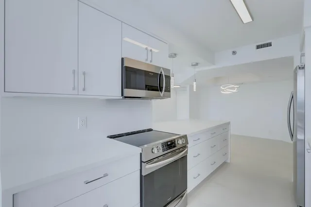 a kitchen with stainless steel appliances white cabinets and a stove top oven