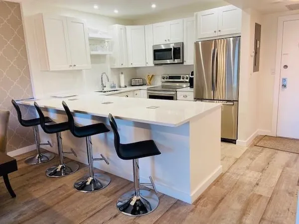 a kitchen with stainless steel appliances a stove a refrigerator a sink a dining table and chairs