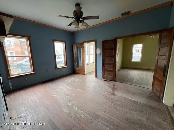 a view of a livingroom with a staircase a ceiling fan and window