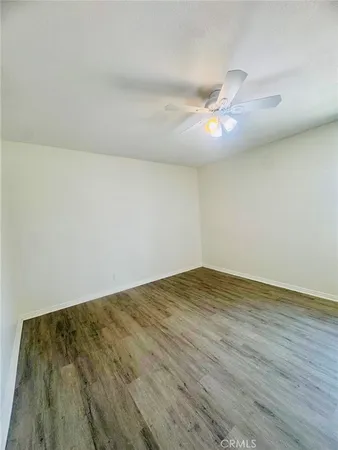 an empty room with wooden floor fan and windows