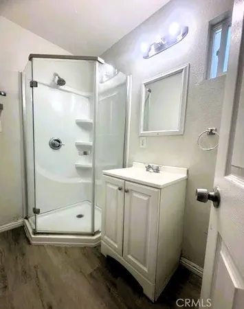 a view of an empty room with wooden floor and a ceiling fan
