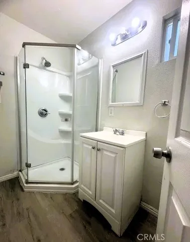 a view of an empty room with wooden floor and a ceiling fan