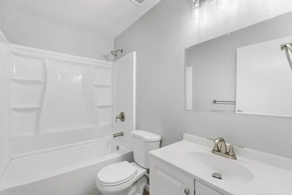 a bathroom with a bathtub shower sink vanity mirror and toilet