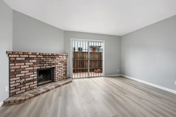 an empty room with wooden floor fireplace and windows