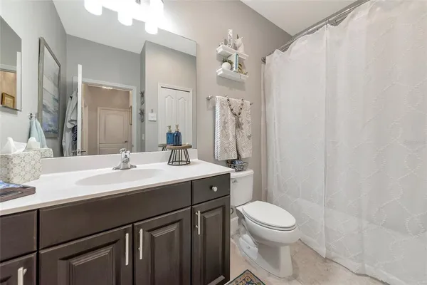 a bathroom with a sink a toilet a mirror a vanity and shower