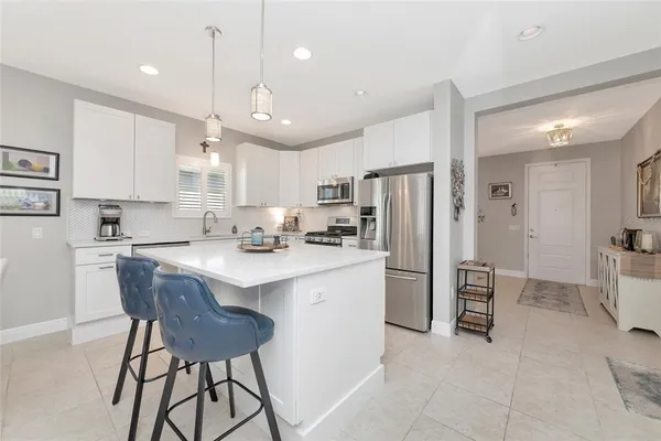 a kitchen with stainless steel appliances granite countertop a table chairs sink refrigerator and cabinets