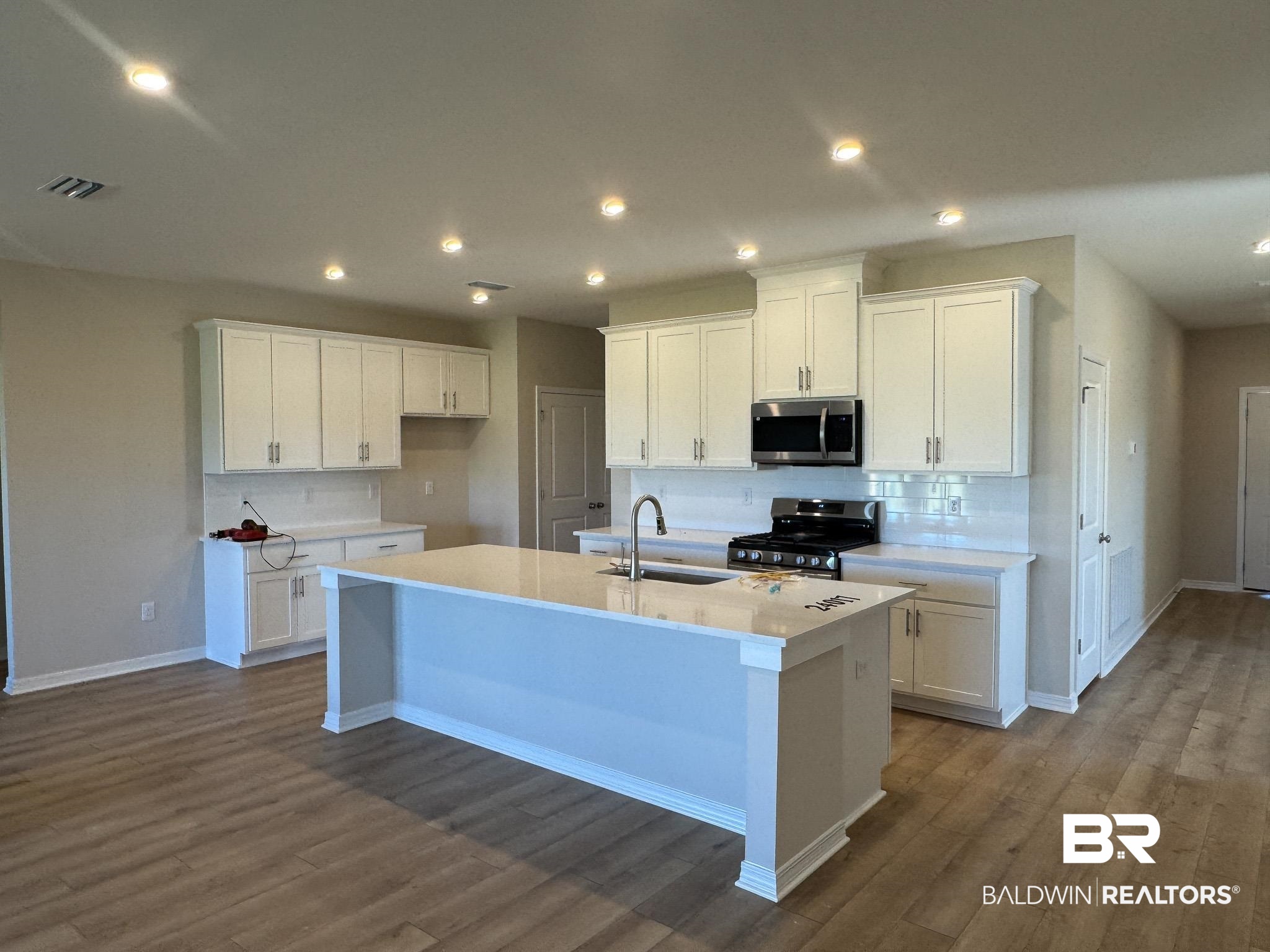 24026 Shadowridge Drive Daphne, AL 36526 - Photo 3 of 11 Kitchen featuring stainless steel appliances, a kitchen island with sink, sink, wood-type flooring, and white cabinets
