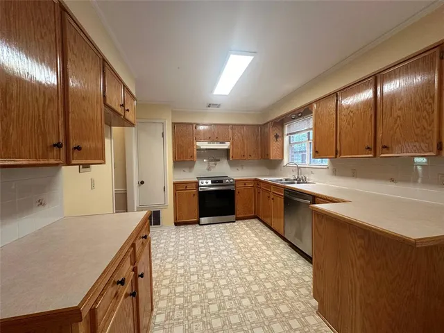 a large kitchen with stainless steel appliances wooden cabinets a sink and a stove