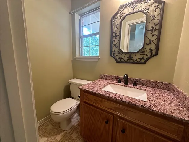 a bathroom with a granite countertop toilet sink and mirror