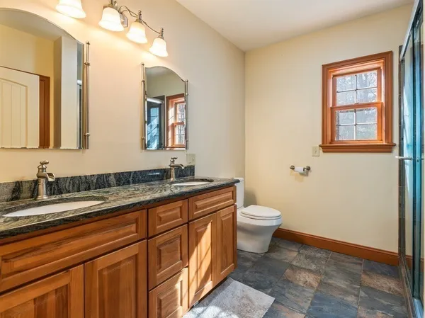 a bathroom with a granite countertop toilet sink and mirror