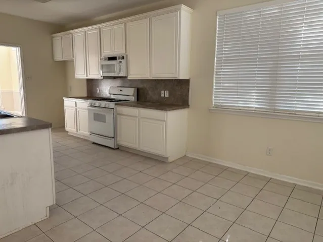a kitchen with granite countertop white cabinets and white appliances