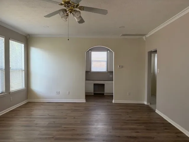 an empty room with wooden floor a ceiling fan and windows