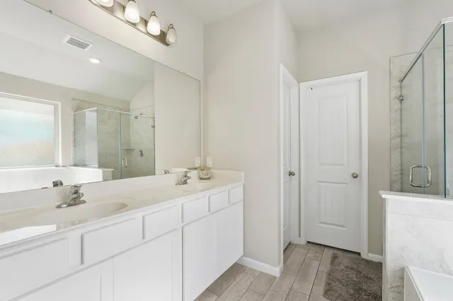 a en suite bathroom with a double vanity sink a mirror and a shower
