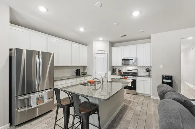 a kitchen with refrigerator a sink and chairs