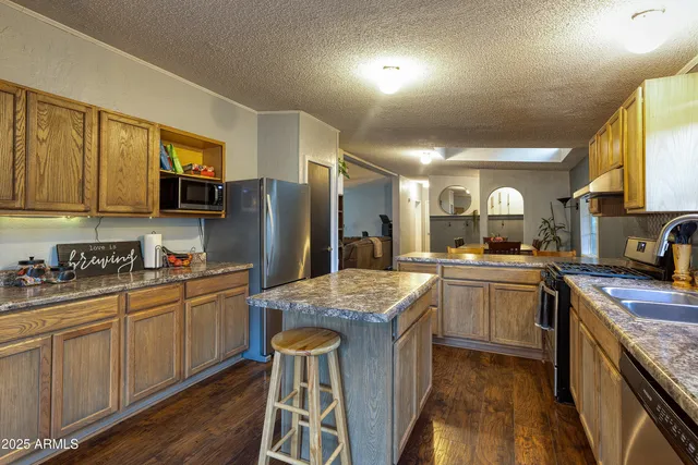 a kitchen with stainless steel appliances granite countertop a refrigerator a sink dishwasher a stove with wooden cabinets and floor