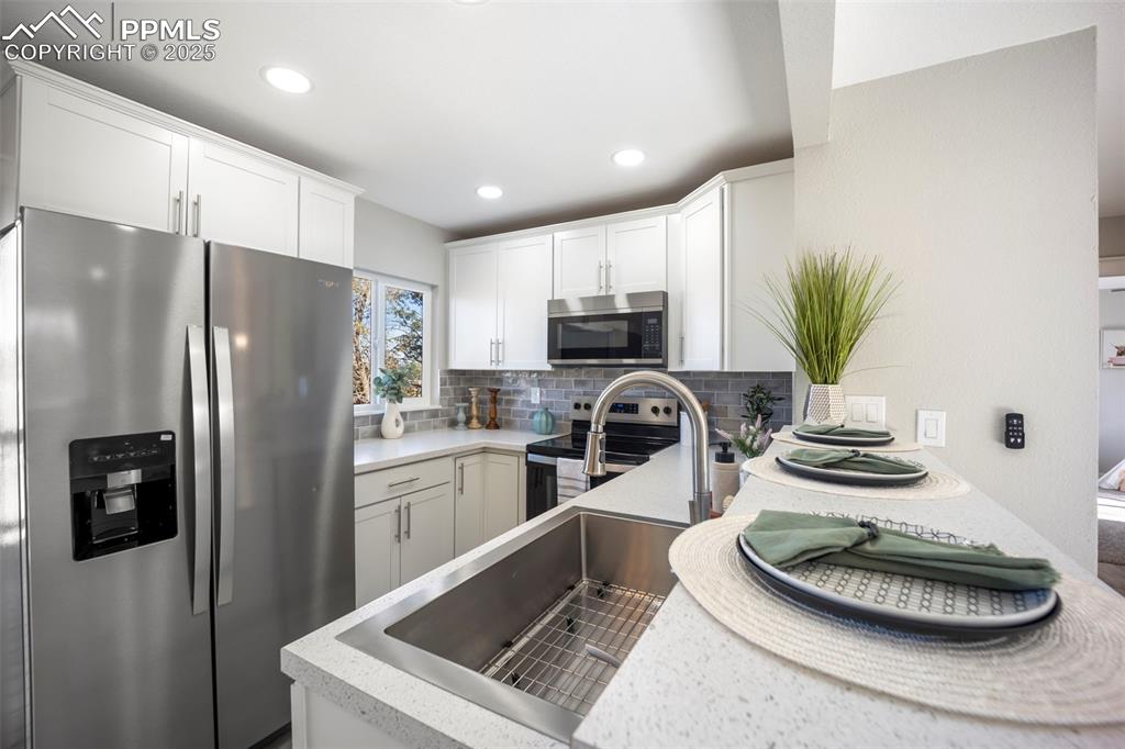 2010 Hampton South Colorado Springs, CO 80906 - Photo 15 of 45 a kitchen with stainless steel appliances a refrigerator a stove a sink a dining table and chairs with wooden floor