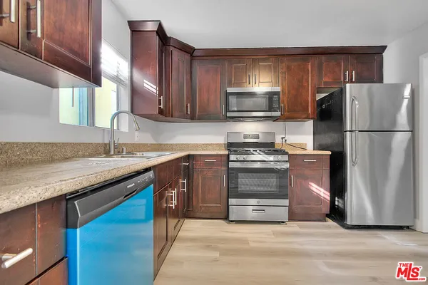 a kitchen with granite countertop a refrigerator stove and sink