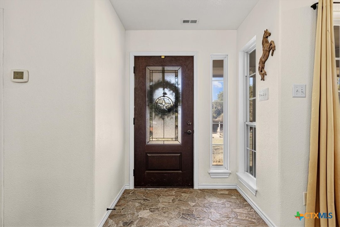 110 Sky Ranch Road Smithville, TX 78957 - Photo 9 of 31 a view of a hallway with wooden floor windows and kitchen view