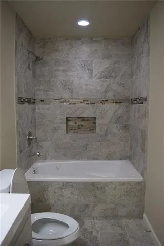a bathroom with a granite countertop toilet and a bathtub