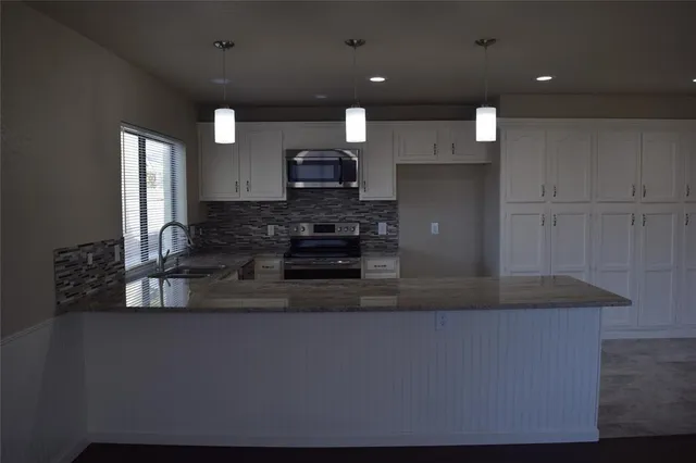 a kitchen with kitchen island granite countertop a sink a stove and cabinets