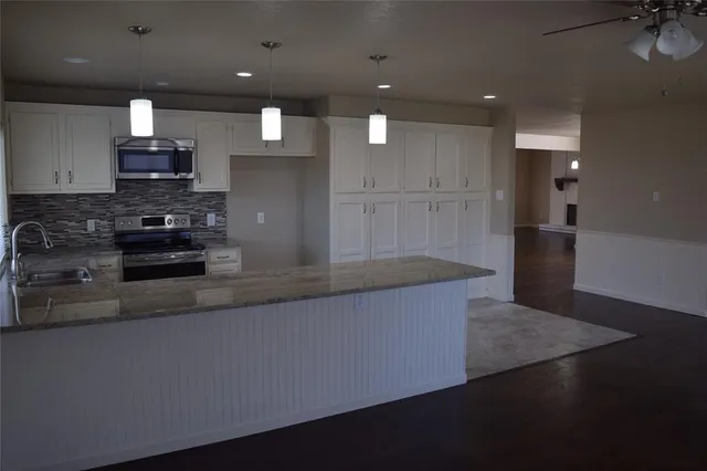 a large kitchen with stainless steel appliances a large counter top a stove and a refrigerator