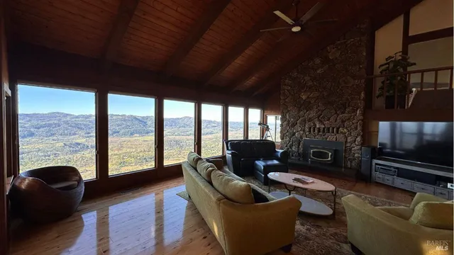 a living room with furniture a flat screen tv and floor to ceiling window