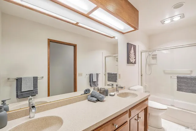 a bathroom with a sink double vanity granite toilet and a mirror
