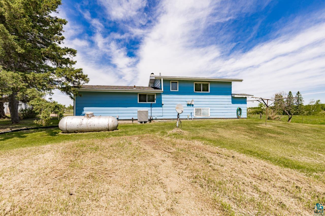 6606 Metso Road Kettle River, MN 55757 - Photo 63 of 84 Expansive grassy lawn surrounds the property, featuring a two-story residence with blue siding and a dark shingle roof