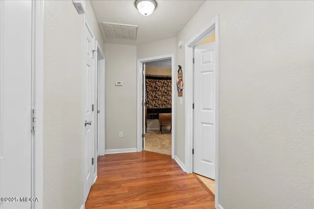 a view of a hallway with wooden floor and closet