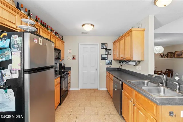 a kitchen with stainless steel appliances granite countertop a refrigerator a stove and a sink