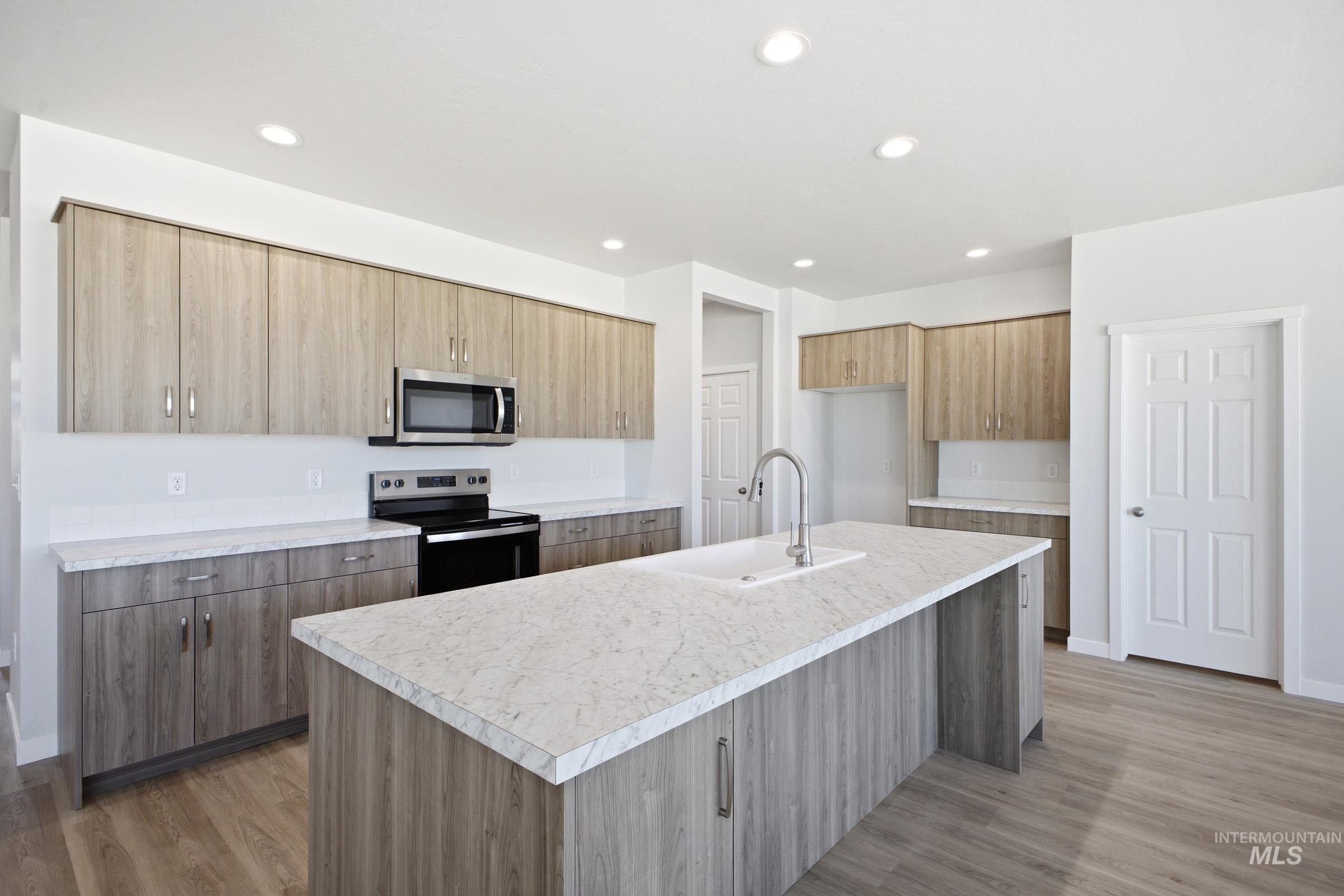 13633 Redway Court Caldwell, ID 83607 - Photo 3 of 29 Kitchen with stainless steel appliances, a kitchen island with sink, light countertops, light wood-style floors, and modern cabinets