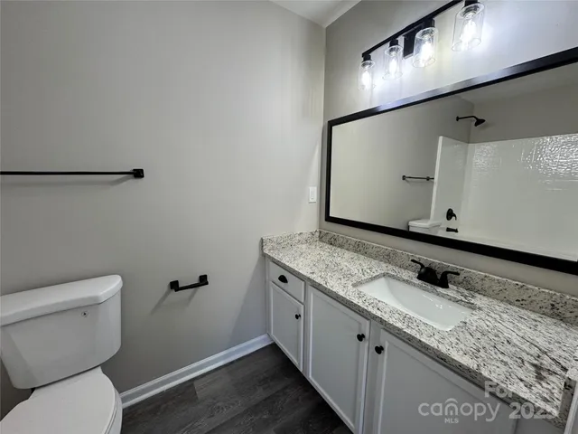 a bathroom with a granite countertop sink a toilet and a mirror