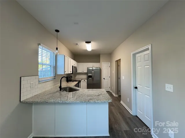 a view of a kitchen with kitchen island a sink wooden floor and a refrigerator