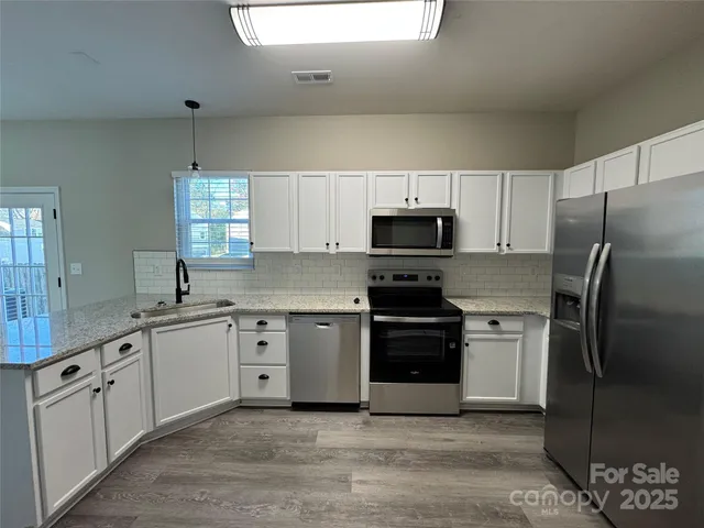 a kitchen with white cabinets sink and stainless steel appliances