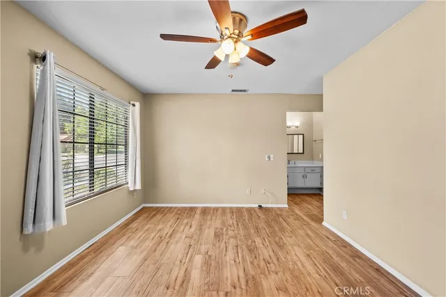 an empty room with wooden floor and ceiling fan
