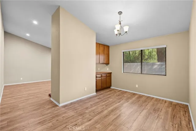 an empty room with wooden floor chandelier and windows