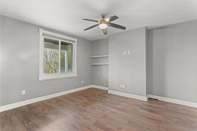 a view of an empty room with a window and wooden floor