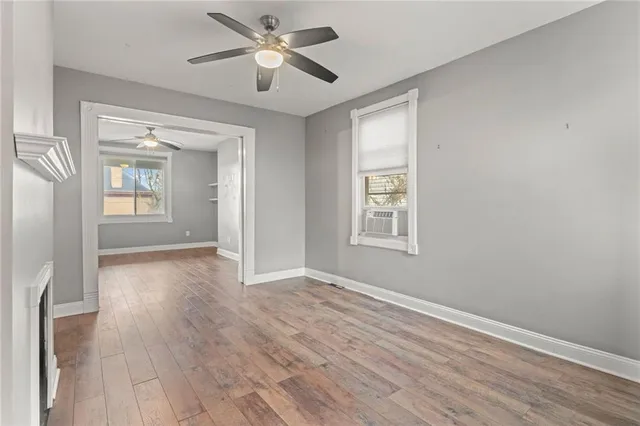 a view of empty room with wooden floor and fan