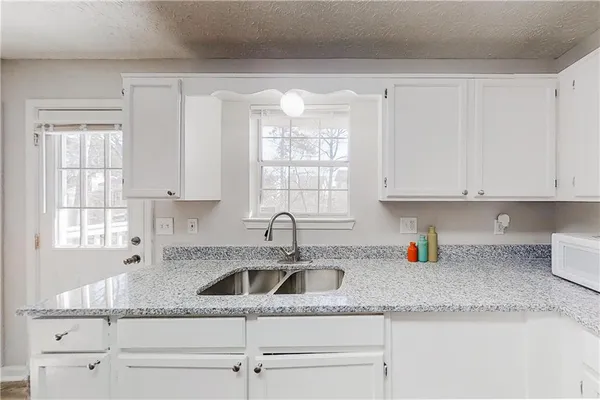 a kitchen with granite countertop white cabinets and a sink