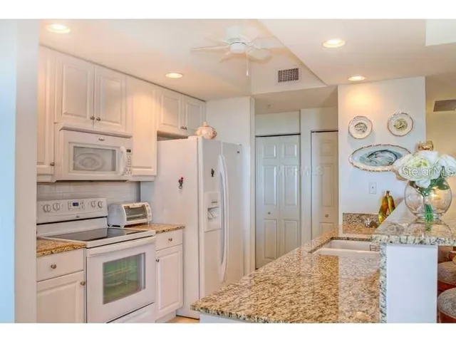a kitchen with stainless steel appliances kitchen island granite countertop a refrigerator and a sink